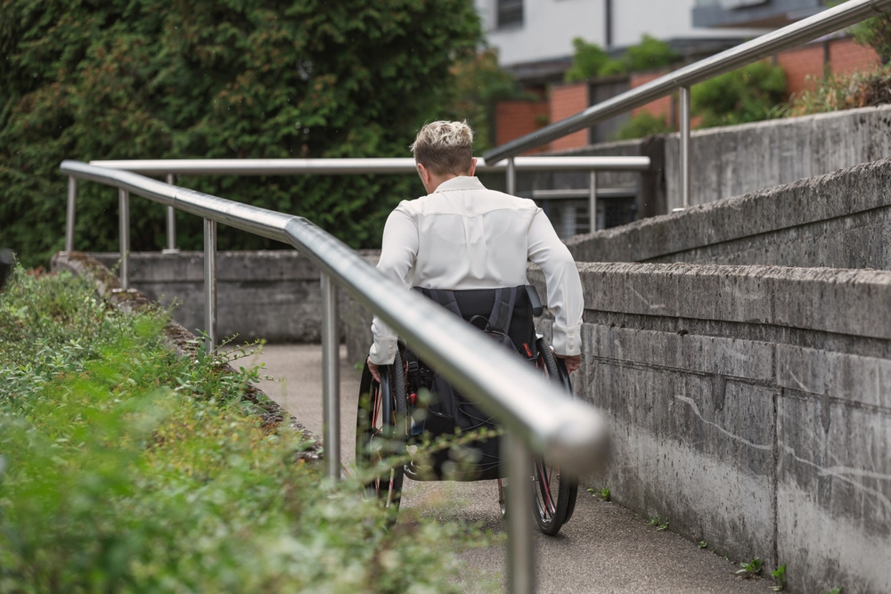 Person with physical disability moving in a manual wheelchair along the access ramp