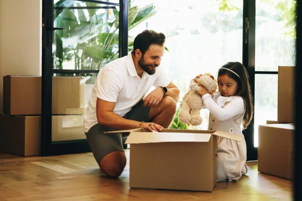 Packing, box and girl with father for moving, property relocation or smile in new home.