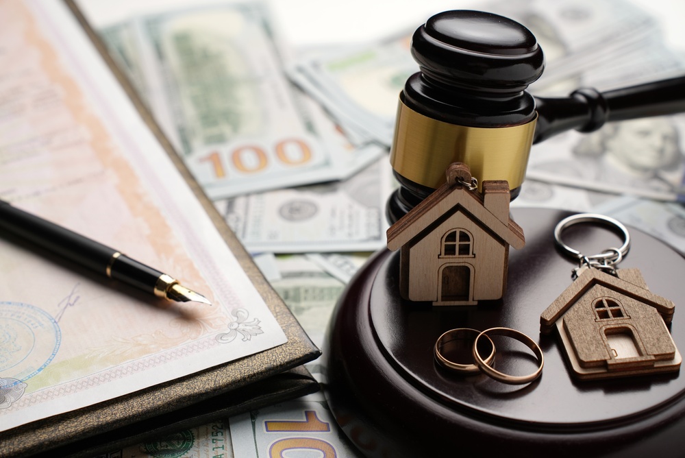 Property Division in Divorce and Marital Law Concept. Gold wedding rings, wooden house model
